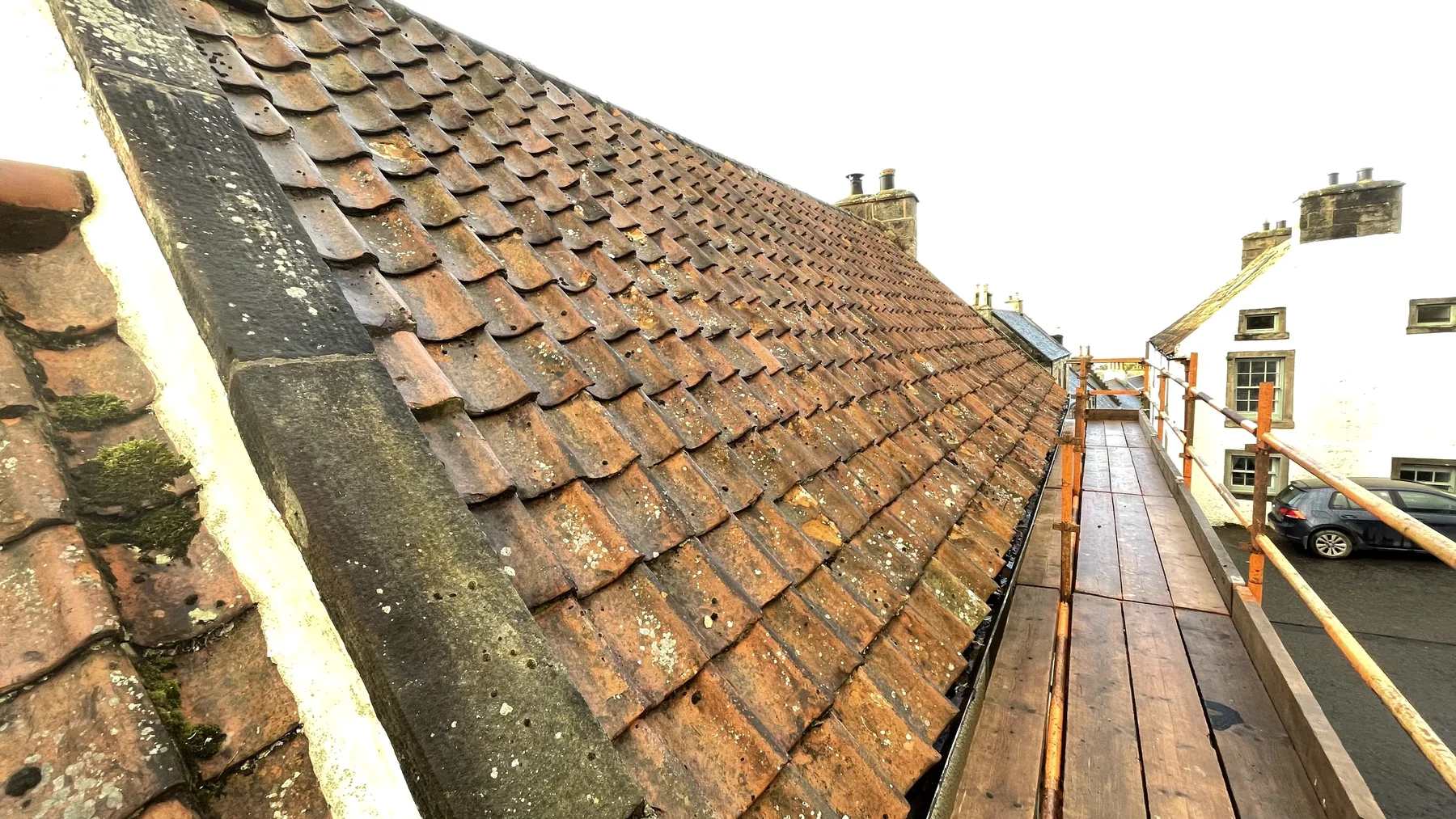 Clay pantiled roof slope with stone skew and scaffolding at Coachman's Cottage near Edinburgh