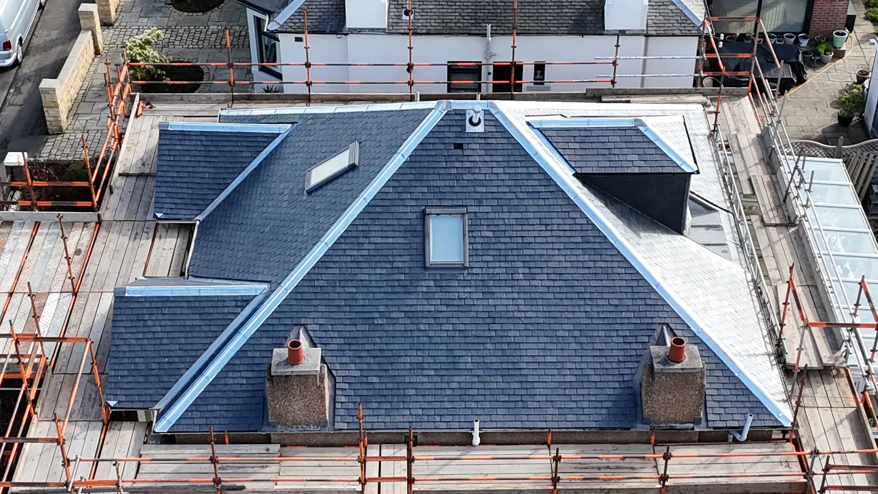 Aerial view of a completed slate roof with new leadwork ridges and skylights in Duddingston, Edinburgh